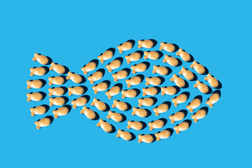 pattern of goldfish snacks in the shape of a large fish on a blue background. minimal concept flat lay
