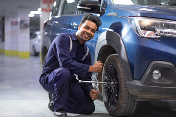 Mechanic changing car tire, during repair and maintenance of a car at a workshop	