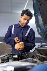 A  mechanic checking motor oil during the maintenance and servicing of a car	