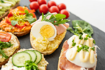 selection board of open sandwiches dips, spreads, cold cut meat, cheese, egg and salad 