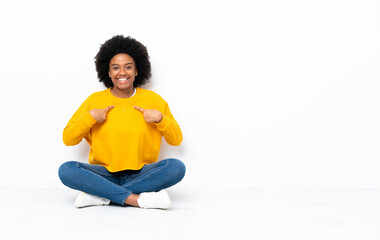 Young African American woman sitting on the floor with surprise facial expression