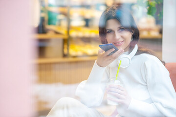 A European woman records and listens to voice messages in a new audio chat, a woman in headphones...