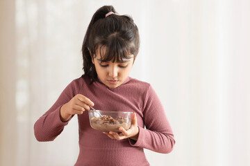 A YOUNG GIRL EATING CHOCOLATE CEREALS	
