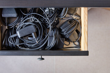 Overhead shot of drawer full of electronics wired chargers.