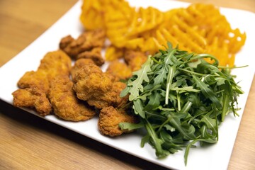 Chicken nuggets with salad on table closeup