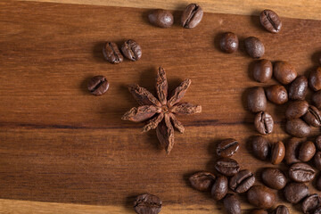 Star anise and roasted coffee beans on a wooden table.