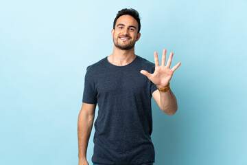 Fototapeta premium Young handsome man over isolated background counting five with fingers
