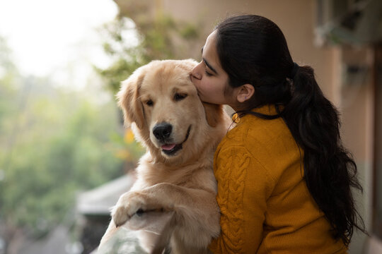 A HAPPY TEENAGER CUDDLING AND KISSING PET DOG	