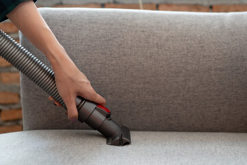 Person doing housework and cleaning sofa.