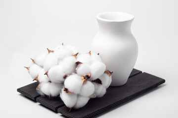 vase and bouquet of cotton on a wooden board