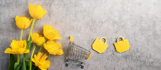 Concept of Mother's day holiday gift shopping with yellow tulip flower on gray background