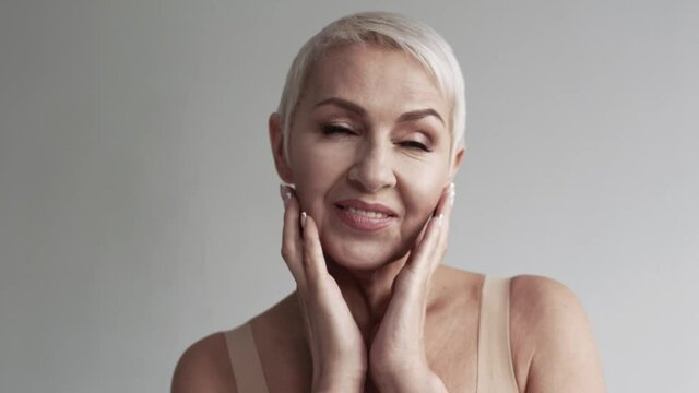 Mature woman touching her face against white background