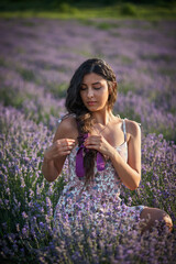 Portrait of lovely brunette girl in lavender field. Summer lavender model posing in front of the camera.