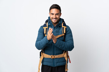 Young mountaineer man with a big backpack isolated on white background applauding