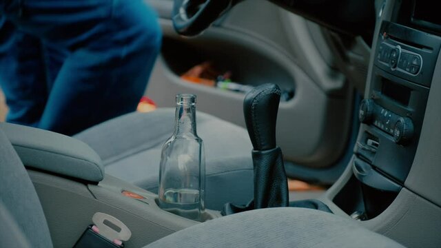 the driver got behind the wheel of his car and reached for a half-empty bottle of alcohol, which is next to the gear lever