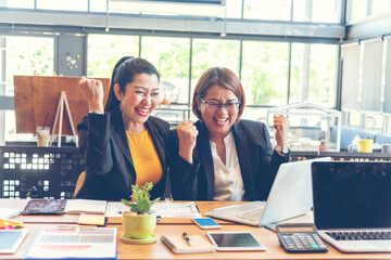 Happy success business woman partner working together in company office corporate executive teamwork. Meeting Executive Asian business woman using laptop office desk with fist arm raised win happiness