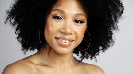 Healthy, Clean, Smooth facial skin. Beauty Portrait of a young female model of Afro-appearance posing.Photo shoot in a photo studio on a white background. Black healthy curly hair.