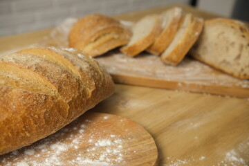 Bread sliced and freshly baked on a wooden table. Flour, bakery. The cooking process is captured in 4k resolution. White brick background. Selective Focus