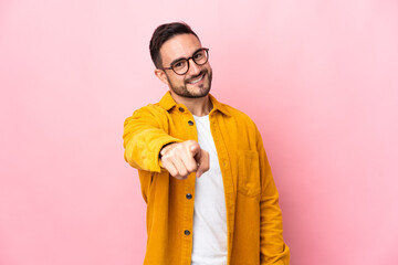 Young caucasian handsome man isolated on pink background pointing front with happy expression