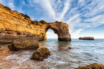 Fototapeta na wymiar Amazing beach at sunrise. Algarve is located in the south of Portugal and is a vacation destination for many tourists. Your stone arch is an excellent spot for photographers and spearfishing