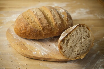 Bread freshly baked on a wooden table. Flour, bakery. The cooking process is captured in 4k resolution. Selective focus. Round loaf