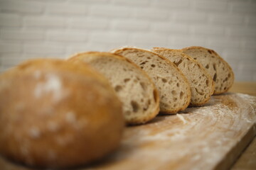 Bread sliced and freshly baked on a wooden table. Flour, bakery. The cooking process is captured in 4k resolution. White brick background. Selective Focus