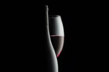 Abwaschbare Fototapete Elegant red wine glass and a wine bottles in black background © Vladimir Razgulyaev