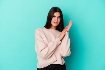 Fototapeta premium Young caucasian woman isolated on blue background feeling energetic and comfortable, rubbing hands confident.