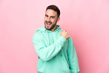 Young caucasian handsome man isolated on pink background celebrating a victory