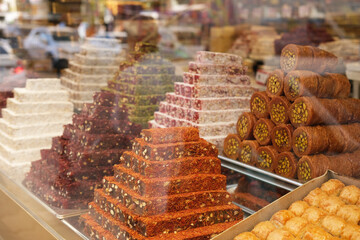 Colorful turkish oriental sweets baklava, cezerye, turkish delight, nougat on the counter in a candy store behind the glass with highlights