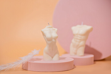 Two trendy soy candle female and male bodies with silver leaf on a pink podium