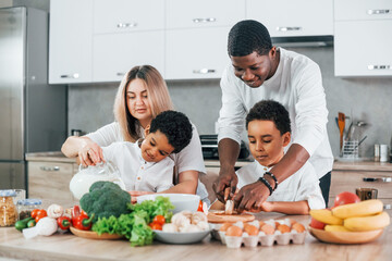 Naklejka premium Multiracial family is together at home at daytime with food on the kitchen. Having breakfast