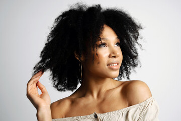 Beautiful smooth facial skin. Portrait of a young female model of Brazilian appearance. Black hair is curly. Photo shoot in a photo studio on a white background. copy space.