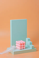 A trendy pink soy cube bubble candle on a blue podium