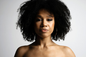 Black hair is curly. Photo shoot in a photo studio on a white background. Portrait of a female model of Afro appearance. copy space. Beautiful smooth facial skin.