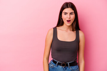 Young caucasian woman isolated on pink background being shocked because of something she has seen.