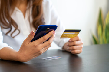 woman holding credit card and using smartphone at home. Businessman or entrepreneur working in office. Online shopping, internet banking, store online, payment, spending money, e-commerce concept.