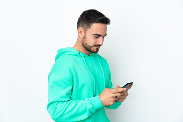 Young caucasian handsome man isolated on white background sending a message or email with the mobile