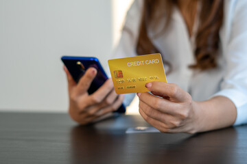 woman holding credit card and using smartphone at home. Businessman or entrepreneur working in office. Online shopping, internet banking, store online, payment, spending money, e-commerce concept.