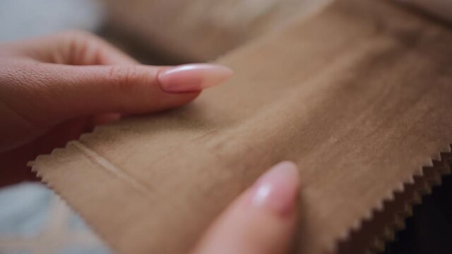 closeup of female hands choosing fabric cloth for curtain at textile showroom