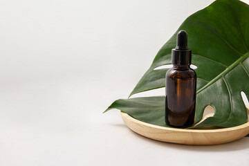 Amber glass cosmetic bottle with green leaf on white background. Blank label for branding mock-up....