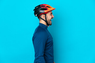 Young cyclist man isolated on blue background laughing in lateral position - obrazy, fototapety, plakaty