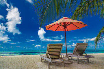 Beautiful tropical island scenery, two sun beds, loungers, umbrella under palm tree. White sand, sea view with horizon, idyllic blue sky, calmness and relaxation. Inspirational beach resort hotel