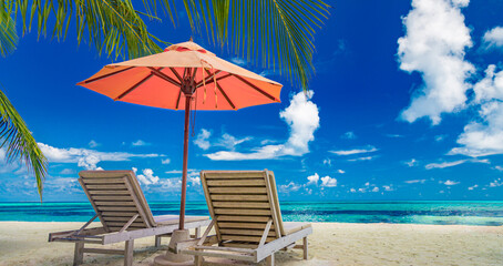 Beautiful tropical island scenery, two sun beds, loungers, umbrella under palm tree. White sand, sea view with horizon, idyllic blue sky, calmness and relaxation. Inspirational beach resort hotel