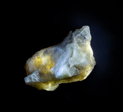 White yellow talk mineral from Ural, Russia. A backlight photo of a stone isolated on black. Geology websites, stone collection catalog, Natural Science museum wall chart or posters