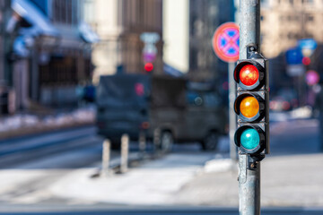 closeup of small traffic semaphore with red light against the backdrop of the city traffic