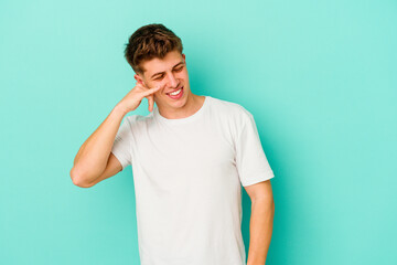 Young caucasian man isolated on blue background showing a mobile phone call gesture with fingers.