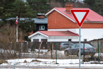 road sign GIVE WAY against the background of a defocused residential area, closeup