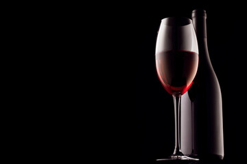 Naklejka na ściany i meble red wine, glass and bottle on a black background, close-up of copy space