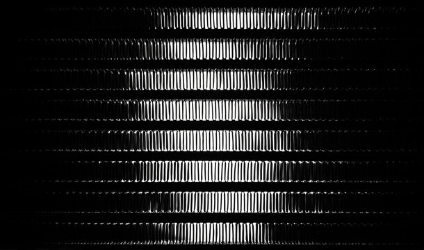 An abstract image of a coil of an automobile radiator of a cooling system, in backlight. The structure of the aluminum plates of the heat sink is visible.